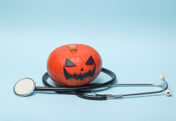 Halloween pumpkin with stethoscope on blue background