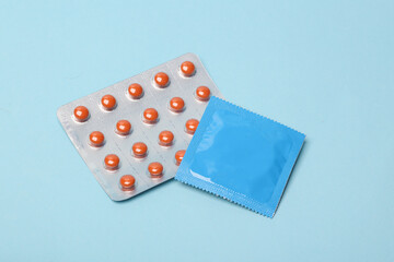 Contraception. Blister of birth control pills with condom package on blue background