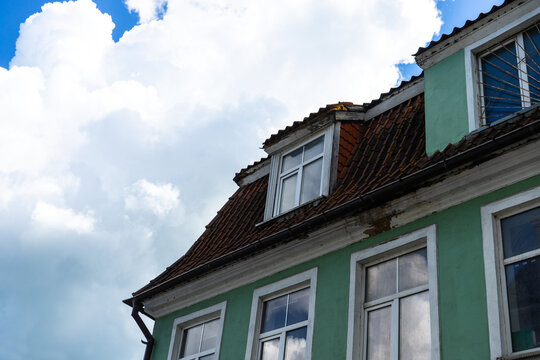 old building with sky and clouds. the roof of the house with nice window. 