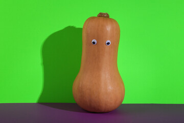 Halloween pumpkin with eyes on green purple background. Creative halloween layout. Minimal still life