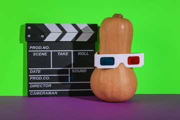 Halloween pumpkin in 3d glasses with movie board on a green-purple background