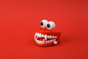 Funny toy clockwork jumping monster teeth with eyes , red background