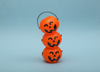 Stack of halloween pumpkins orange candy buckets with face on blue background. Trick or Treat