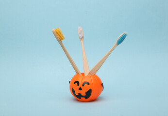 Halloween pumpkins orange candy bucket with toothbrushes on blue background. Trick or Treat. Dental...