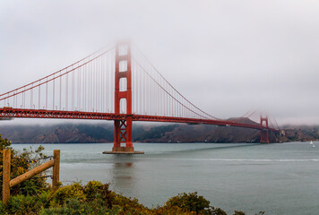 The famous Golden Gate bridge on a cloudy summer day with low hanging fog rolling in San Francisco, California
