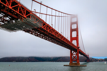 The famous Golden Gate bridge on a cloudy summer day with low hanging fog rolling in San Francisco, California