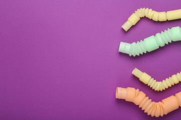 Many Antistretch pop tube toys on purple background with copy space. Top view