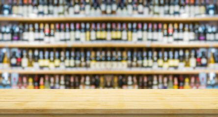 Empty wood table top with blur wine bottles on liquor alcohol shelves in supermarket wine store...