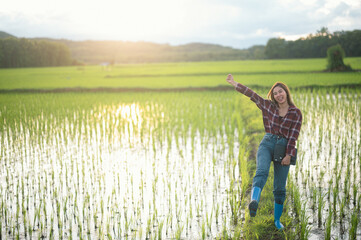 An Asian woman farmer happy looks at his own field after planting rice.