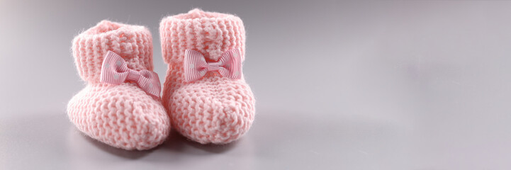 Pink knitted slippers for newborn on gray background