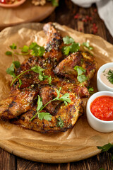Traditional georgian dish - chicken tabaka on wooden background in rustic style. Roasted whole chicken in georgian style on wooden table. Chicken tabaka with sauces in rustic style.