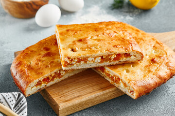 Apricot pie on wooden board in rustic style. Closed pie with apricot and cottage on concrete background. Sweet pastry - fruit pie with dried apricot.