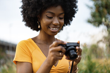 Smiling African american woman using professional camera at a street