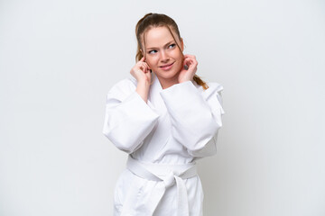 Young caucasian girl doing karate isolated on white background frustrated and covering ears