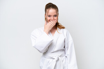 Young caucasian girl doing karate isolated on white background happy and smiling covering mouth...