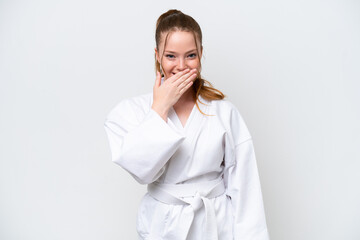 Young caucasian girl doing karate isolated on white background happy and smiling covering mouth with hand © luismolinero
