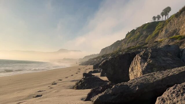 4k Foggy Malibu Beach Blue and Green Ocean waves crash into the rocky shore on a cloudy day b roll