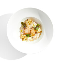 Delicious creamy risotto with sea scallop and cauliflower. Elegant main course with seafood on white plate. Grilled scallop with cauliflower and creamy rice. Seafood risotto with scallops.