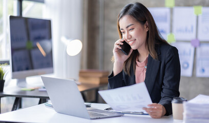 Young Business asian woman talking on smartphone and working in office. Asian female Business sitting at his workplace.