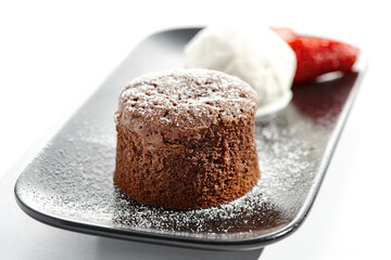 Chocolate fondant with ice cream ball on black plate. Traditional French dessert - chocolate cake with ice cream and strawberry. Lava cake isolated on white background. Hot cocoa pudding.