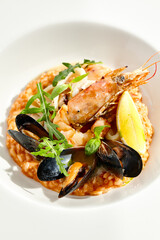 Italian dish - seafood risotto on white plate. Risotto frutti di mare with shrimp, mussels and squid. Seafood in marinara sauce with arborio rice. Paella with prawn and mussels. Seafood menu.