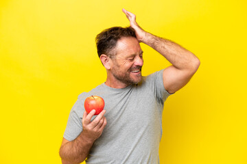 Middle age caucasian man with an apple isolated on yellow background has realized something and intending the solution
