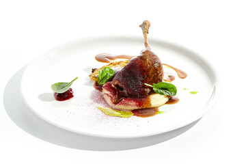 Delicatessen dish - duck leg confit with mashed potatoes and cabbage steak. Duck confit with vegetables and wine gravy on white plate. Gourmet meal in restaurant menu. Fusion main course.