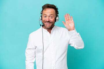 Telemarketer caucasian man working with a headset isolated on blue background saluting with hand with happy expression