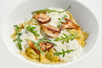 Mushroom ravioli and cheese sauce isolated on white background. Italian dish - ravioli with porcini and creamy espuma on white plate. Restaurant dishes with wild mushroom.