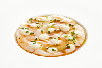 Delicious food - sea scallop carpaccio in yuzu sauce on white background. Scallop ceviche in japanese style. Scallop crudo in citrus sauce and creamy espuma. Delicacy seafood in restaurant menu.