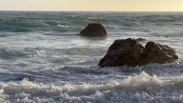 4k Malibu Beach Blue and Green Ocean waves crash into the rocks and shore on a cloudy day b roll