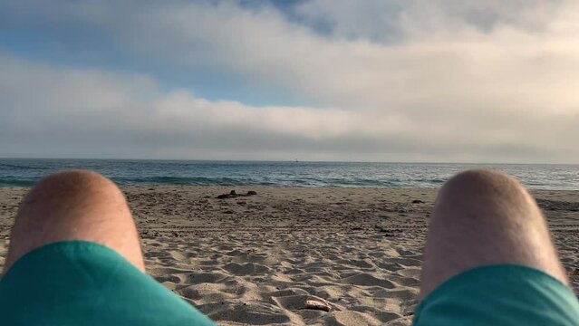 4k Malibu Beach Blue and Green Ocean as seen through the legs of a man waves crash into the shore on a cloudy day b roll