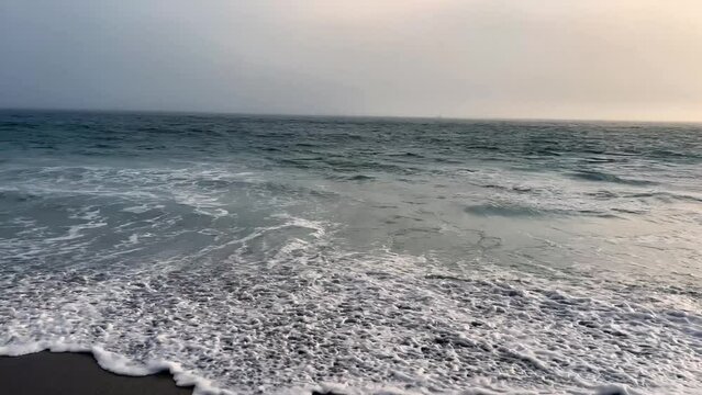 4k Malibu Beach Blue and Green Ocean waves crash into the shore on a cloudy day b roll