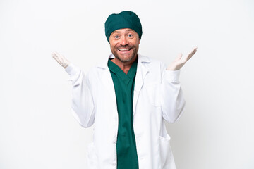 Middle age surgeon in green uniform isolated on white background with shocked facial expression