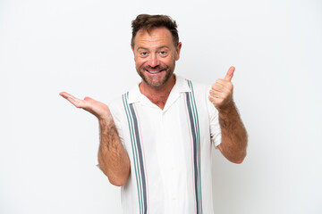 Middle age caucasian man isolated on white background holding copyspace imaginary on the palm to insert an ad and with thumbs up