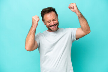 Fototapeta premium Middle age caucasian man isolated on blue background celebrating a victory