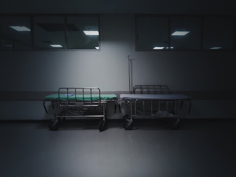 Hospital emergency bed. An empty bed in the dark corner of the ward. Illness and death concept.