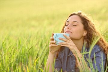 Woman enjoying holding coffee cup in a wheat field