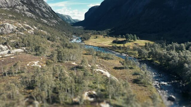 Aerial view of the river flowing through the wide rocky valley. Pan forward.