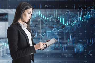 businesswoman with tablet and creative glowing forex chart hologram with map on blurry office interior background. Stock, market and invest concept. Double exposure.