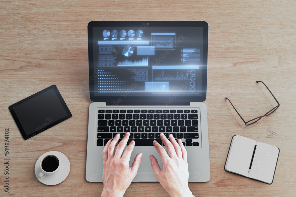 Poster man hands using laptop keyboard with glowing business chart hologram on screen at wooden desktop wit
