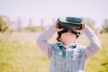 A boy is playing virtual reality glasses on the street . Modern gadgets. Children's games. The choice of virtual glasses. An article about virtual glasses. Modern children.