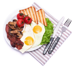 Fried eggs, bacon, tomato and toasted bread in ceramic plate isolated on white background