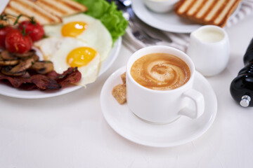 Fried eggs, bacon, tomato, toasted bread in white ceramic plate and cup of coffee
