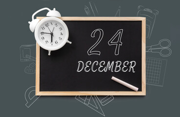 december 24. 24th day of month, calendar date. Blackboard with piece of chalk and white alarm clock on green background. Concept of day of year, time planner, winter month