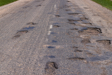 poor paved road with a lot of holes and potholes