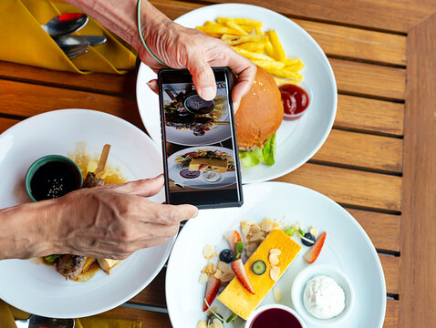 Smartphone picture as man hands takes photography by smartphone of food  grilled burgers,swwet cheese cake for ,social media concept