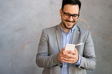 Handsome businessman checking emails on the phone in modern office in coffee break