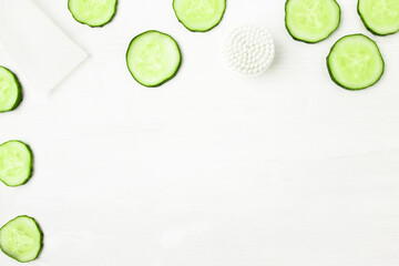 Skin care cosmetics with fresh cucumber slices on white wooden background with copy space, flat lay.