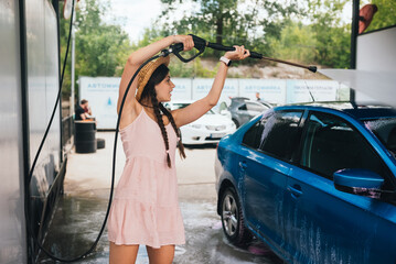 Brunette from a high-pressure hose washes the car